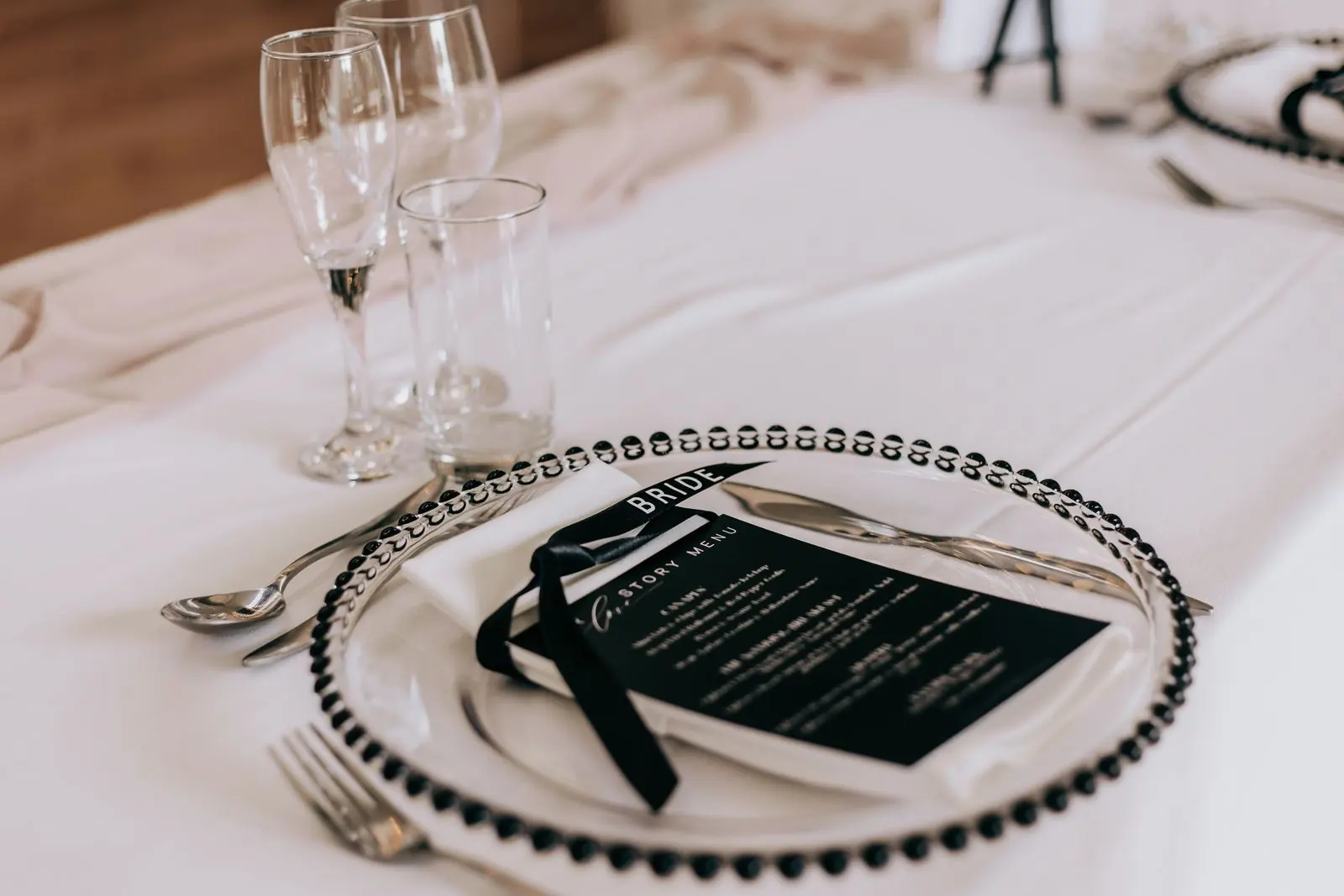 Black menu card on a glass charger plate at the wedding breakfast