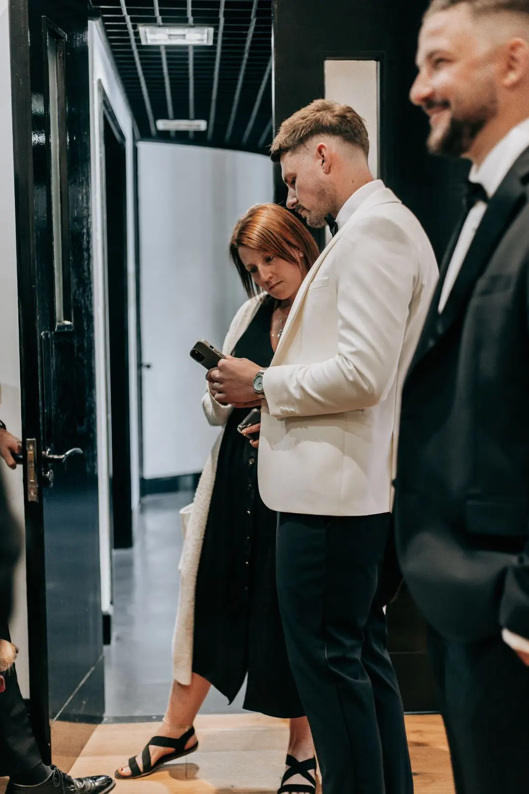 Groom in a white jacket laughing with a guest