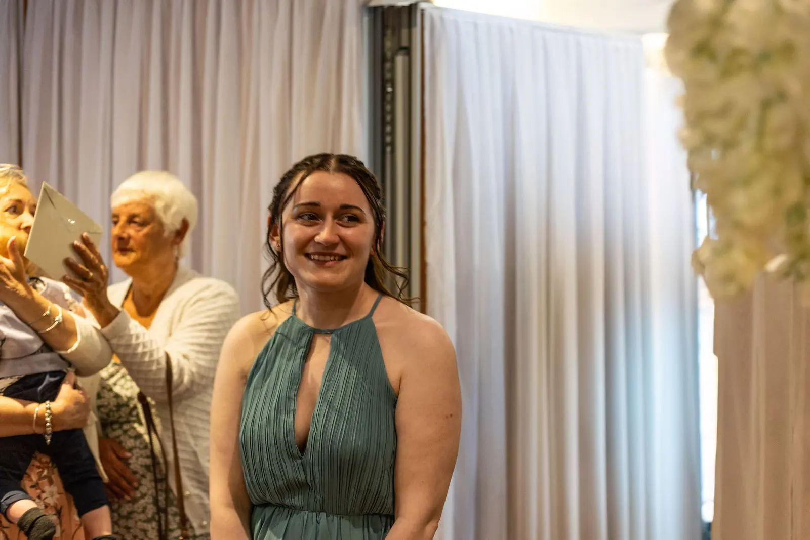 Bridesmaid smiling before the ceremony while guests chat