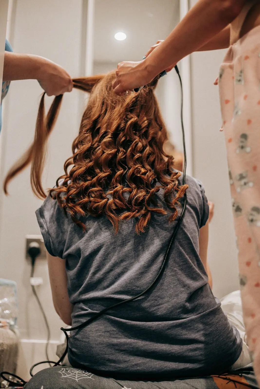 Bridesmaid curling the bride's long hair