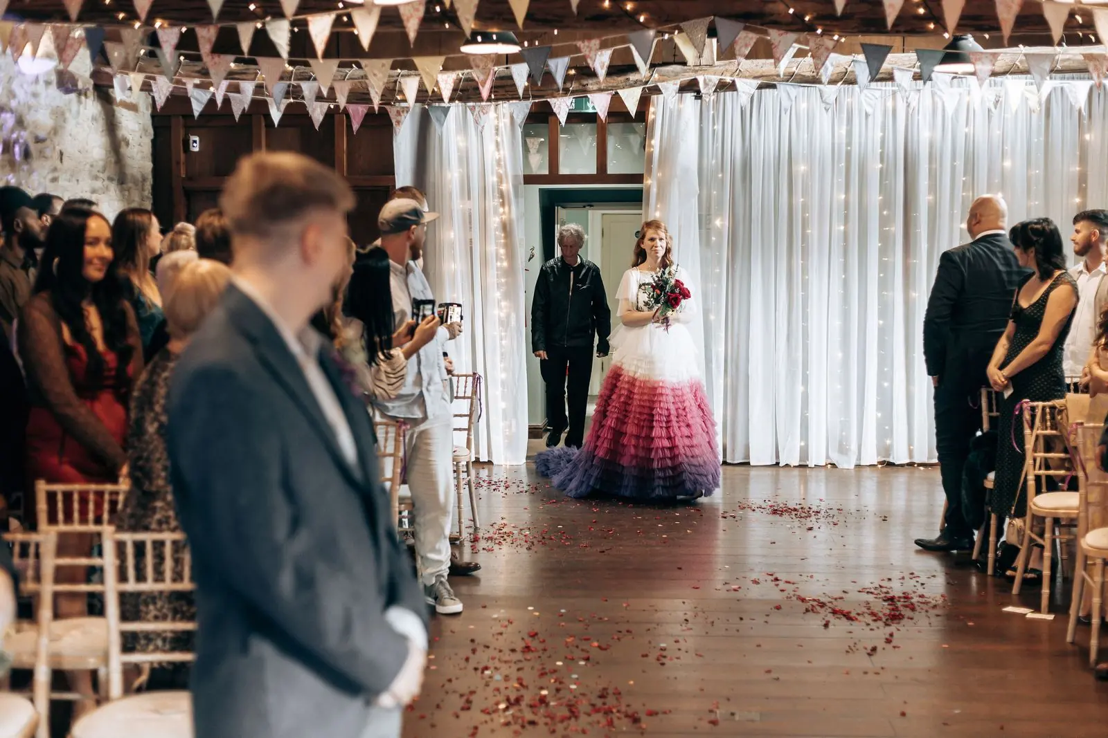 Bride walking down the aisle past guests while the groom looks on