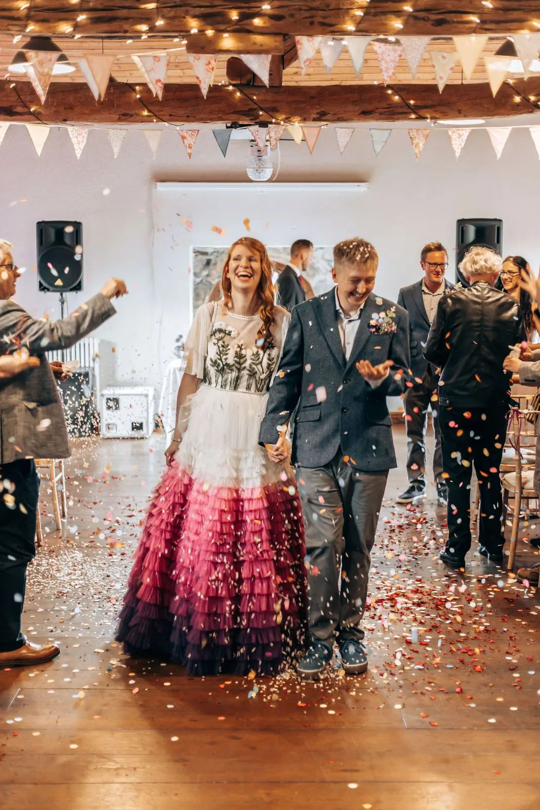 Couple walking back down the aisle through confetti