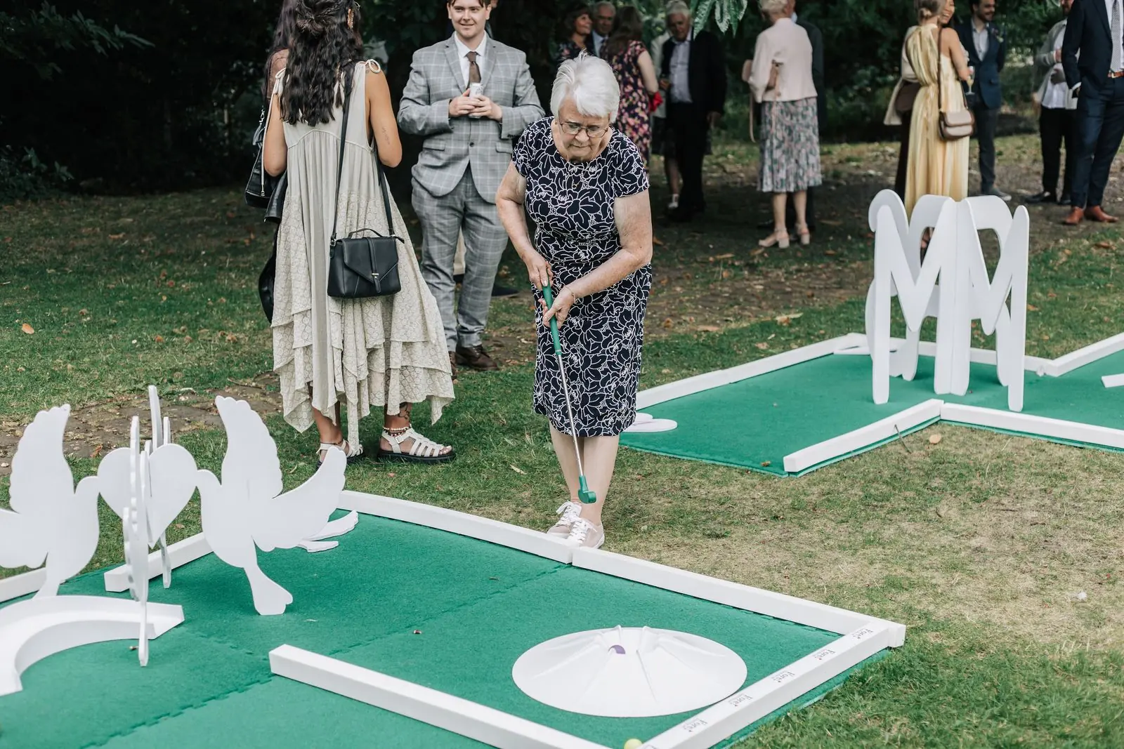 Guests playing crazy golf on the lawn at the wedding